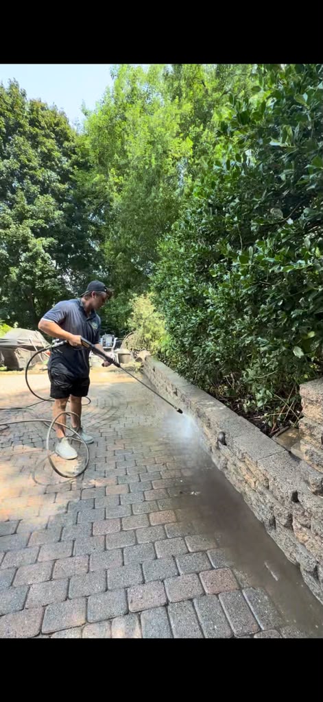Technician surface cleaning a paver patio with a pressure washer