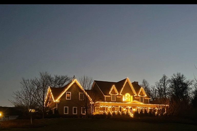 Large Hudson Valley home outlined with warm white holiday lights