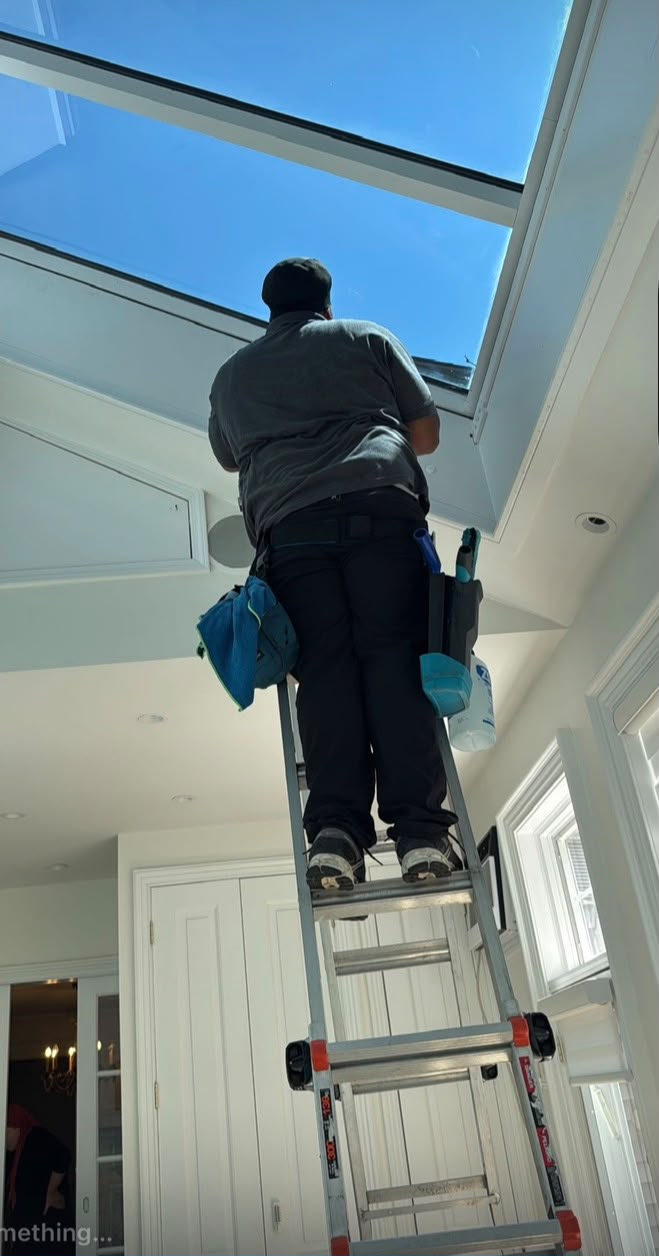 Technician on a ladder cleaning an interior skylight
