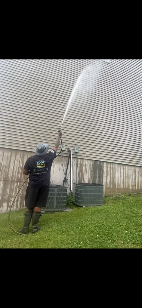 Edge Shines technician soft washing siding above AC units