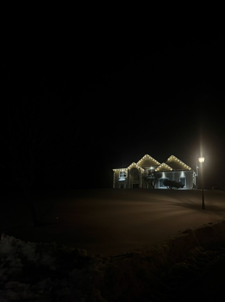 Snow-covered home with professionally installed white holiday roofline lights