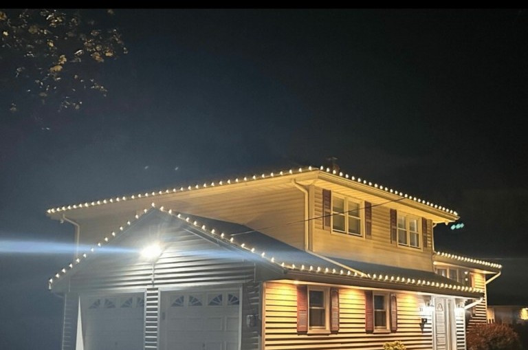 Two-story home and garage finished with clean warm white holiday lights