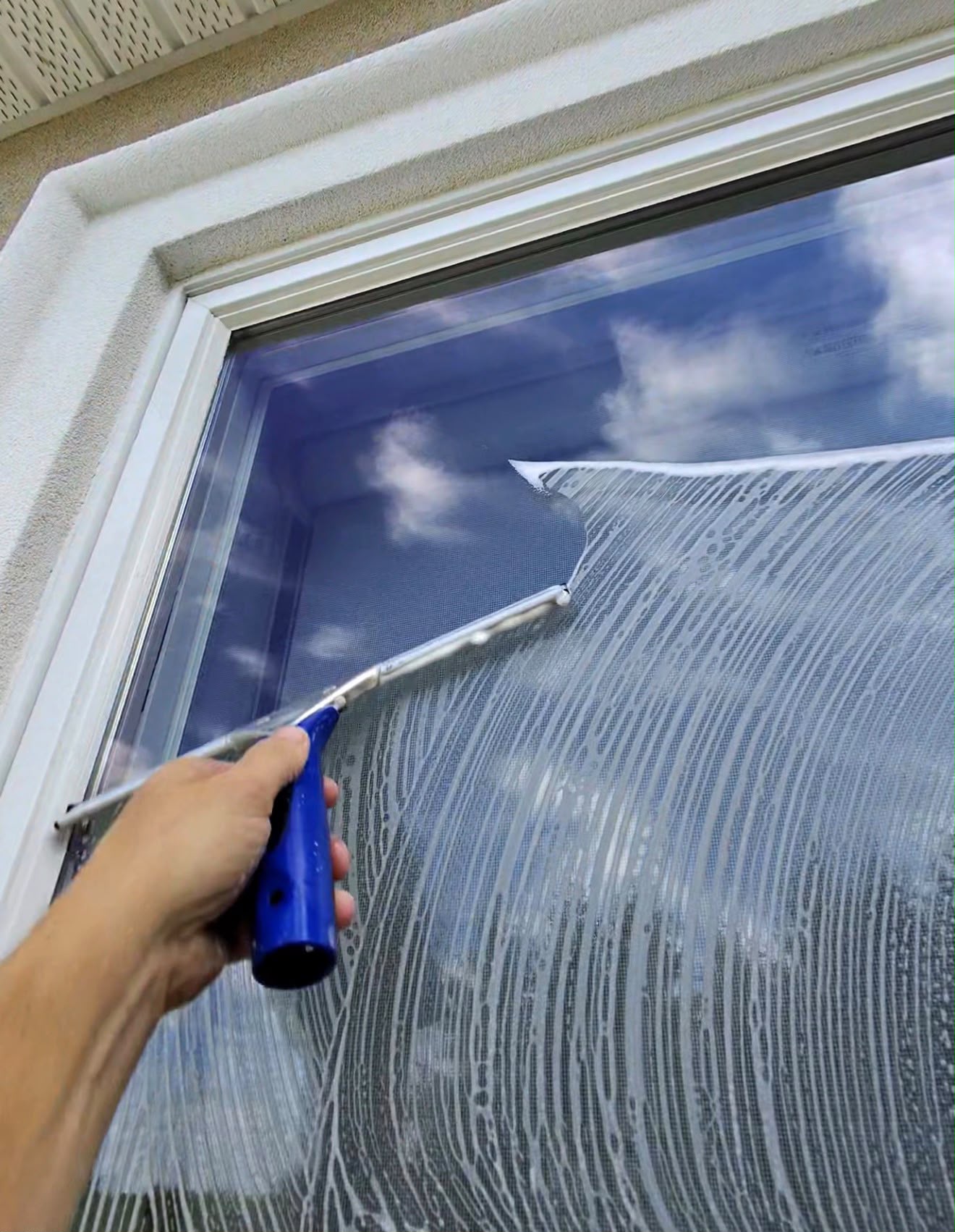 Squeegee pulling soap from a freshly washed window