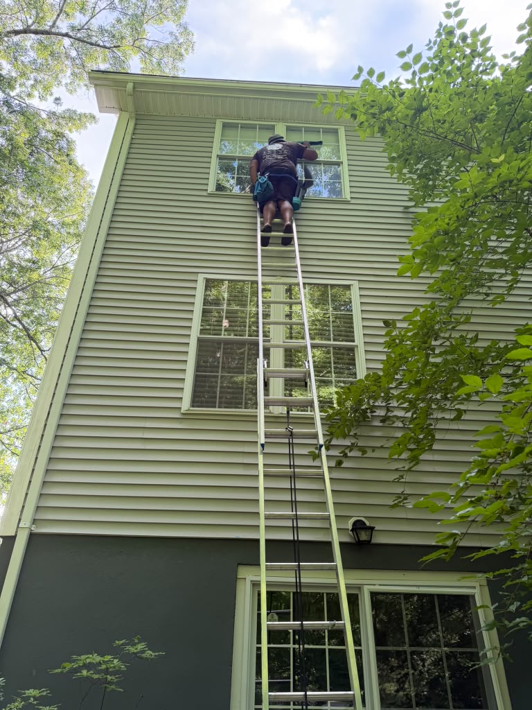 Technician on a ladder cleaning second story windows